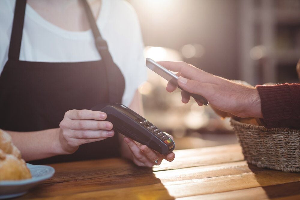 customer putting phone next to credit card reader for payment